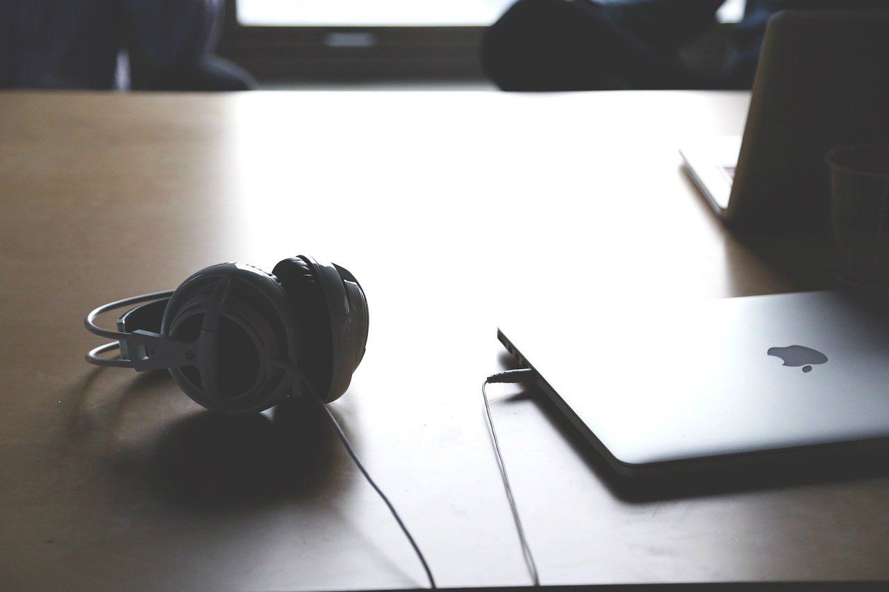 A computer, headphones on a desk.