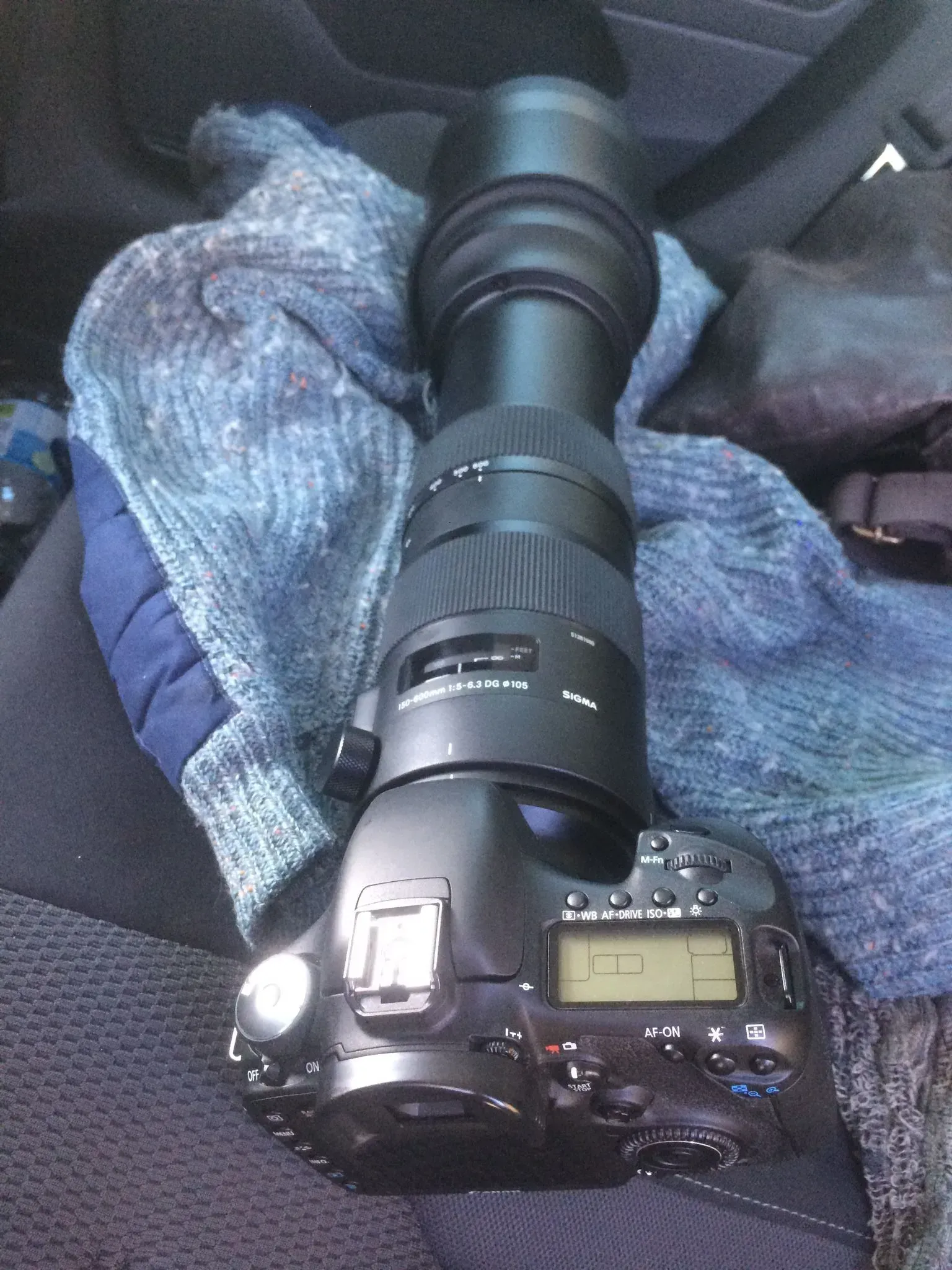 Una macchina fotografica adagiata su un sedile di un'automobile e su un asciugamano.