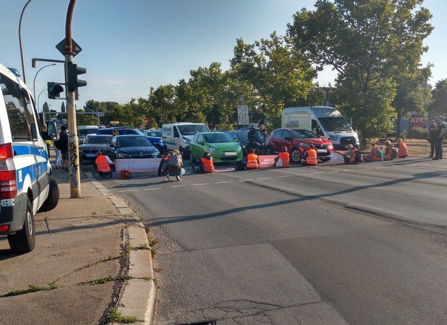 Straßenblockade, 12 blockierende (10 zu sehen), Polizei vor Ort