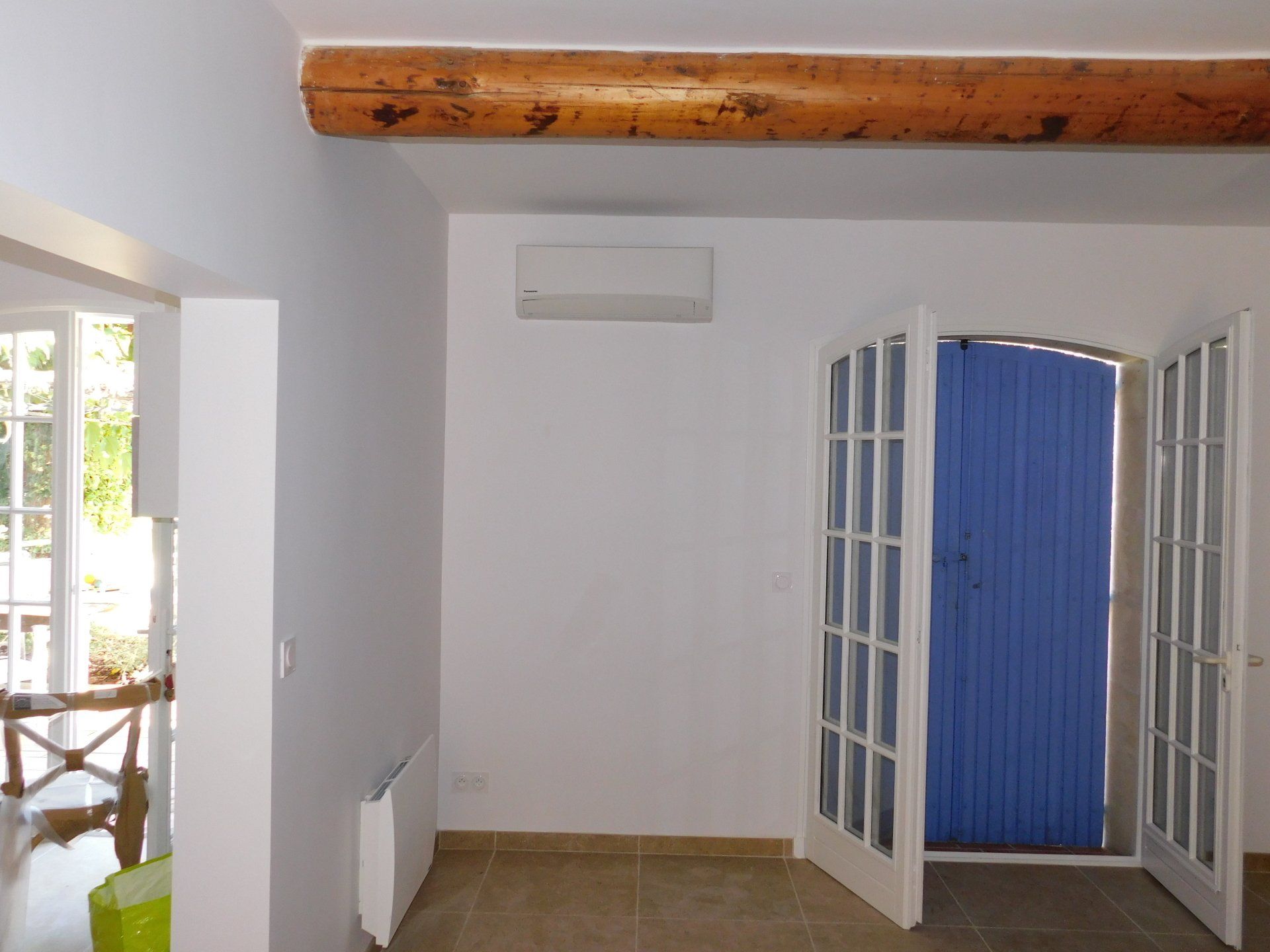 petit climatiseur intérieur sur un mur à coté d'une porte d'entrée bleue