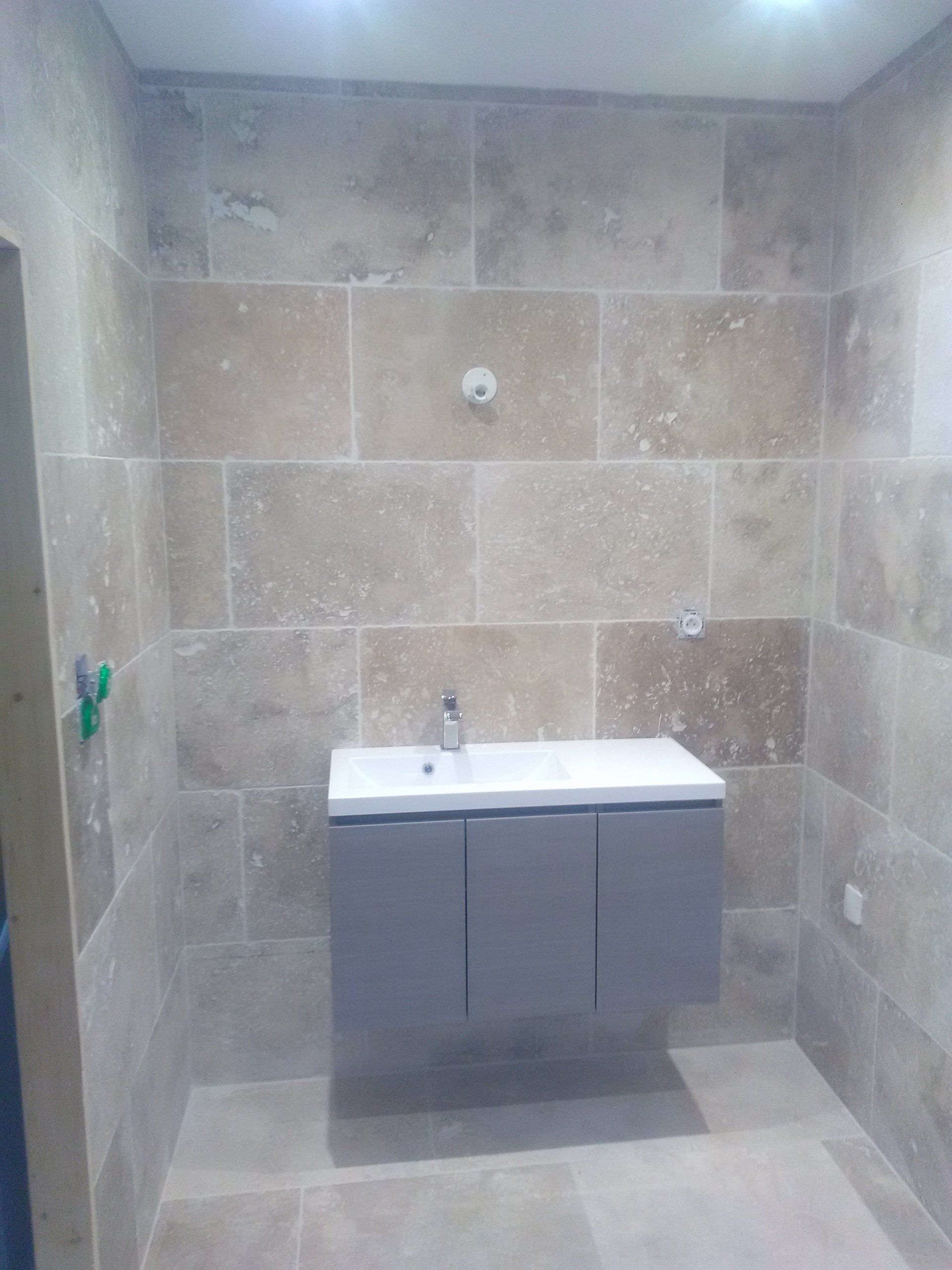 lavabo dans une salle carrelée de beige et marron clair