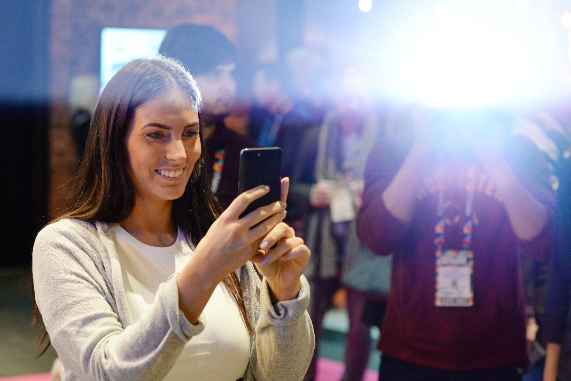 Eine Messemitarbeiterin mit Smartphone – im selben Moment von einem Eventfotografen fotorafiert.