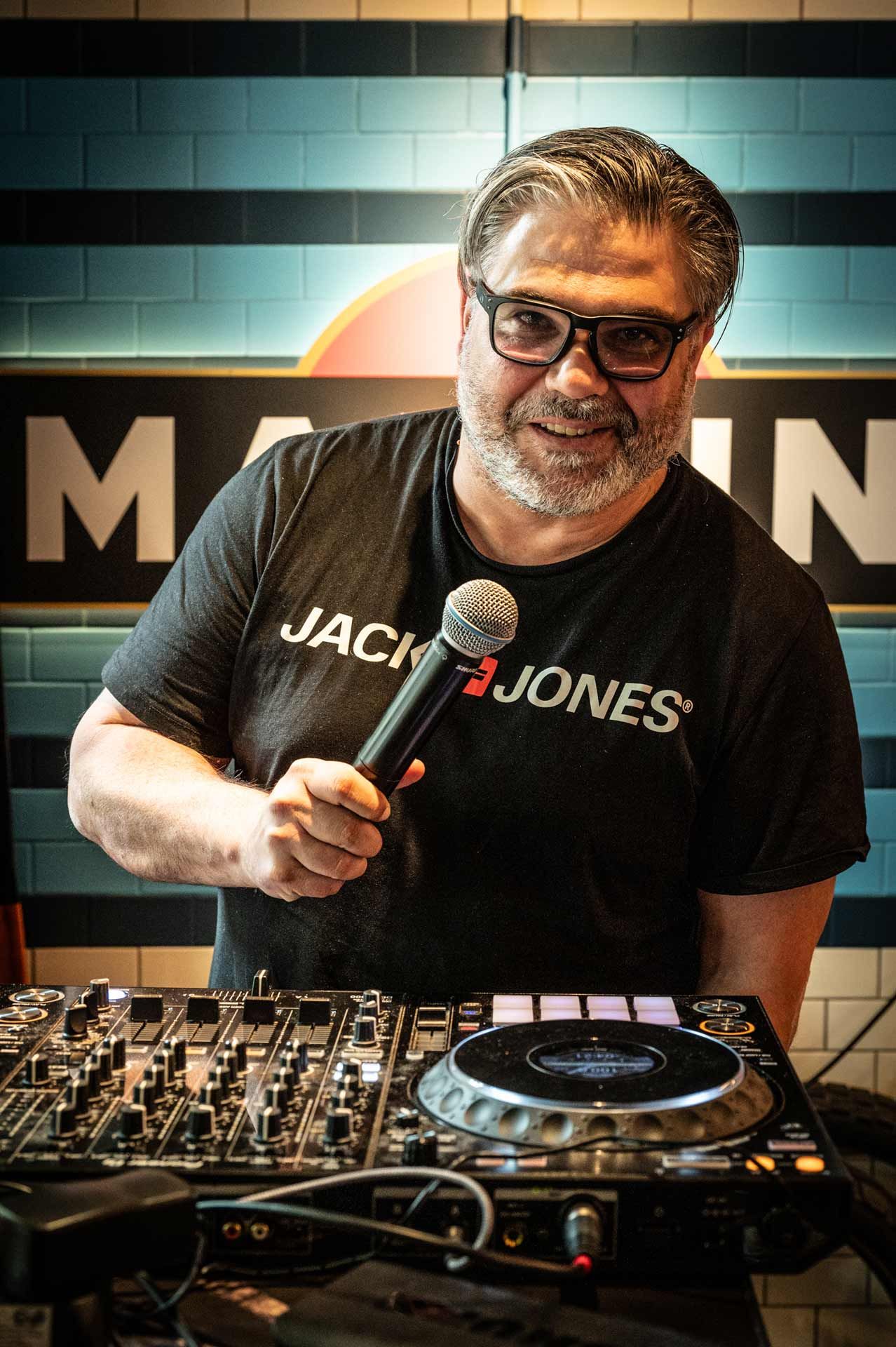 Eventfotografie Hamburg – Symbolbild für die FAQs mit Antworten zum Ablauf eines Event-Shootings, hier ein DJ mit Mikrofon am Mischpult.