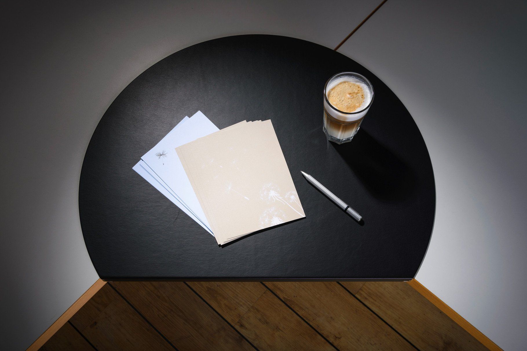 Eine schwarze Schreibtischauflage aus Leder von ip20 auf einem Schreibtisch mit Briefpapier und einem Kaffee, Werbefotografie aus Hamburg von Fotograf Kay Winter / WINTERPOL