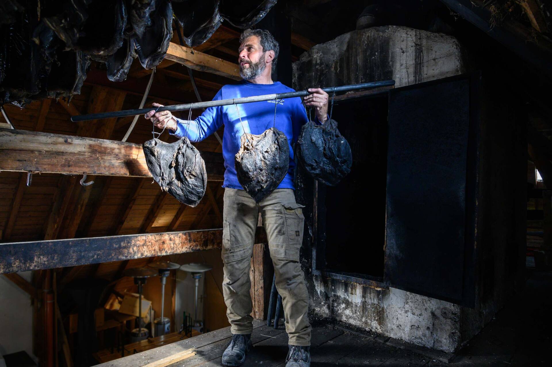 Ospelehof Hinterzarten– Reportage-Fotografie von WINTERPOL Hamburg Der Besitzer des Ospelehof Hinterzarten hängt frisch geräucherten Schinken zum Trocknen auf – Reportage-Fotografie von WINTERPOL Hamburg