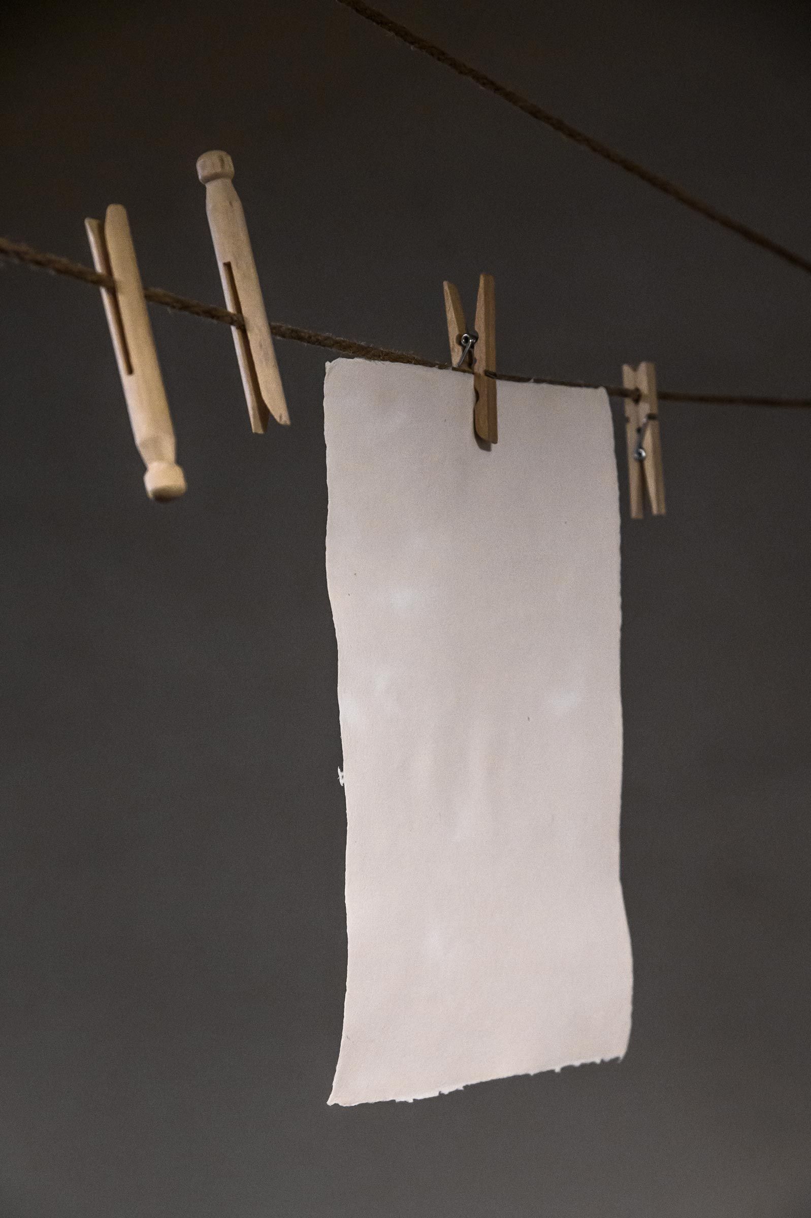 In der Papierfabrik Gmund hängt ein Blatt Büttenpapier an einer Wäscheleine zum Trocknen – Reportage-Fotografie von WINTERPOL Hamburg
