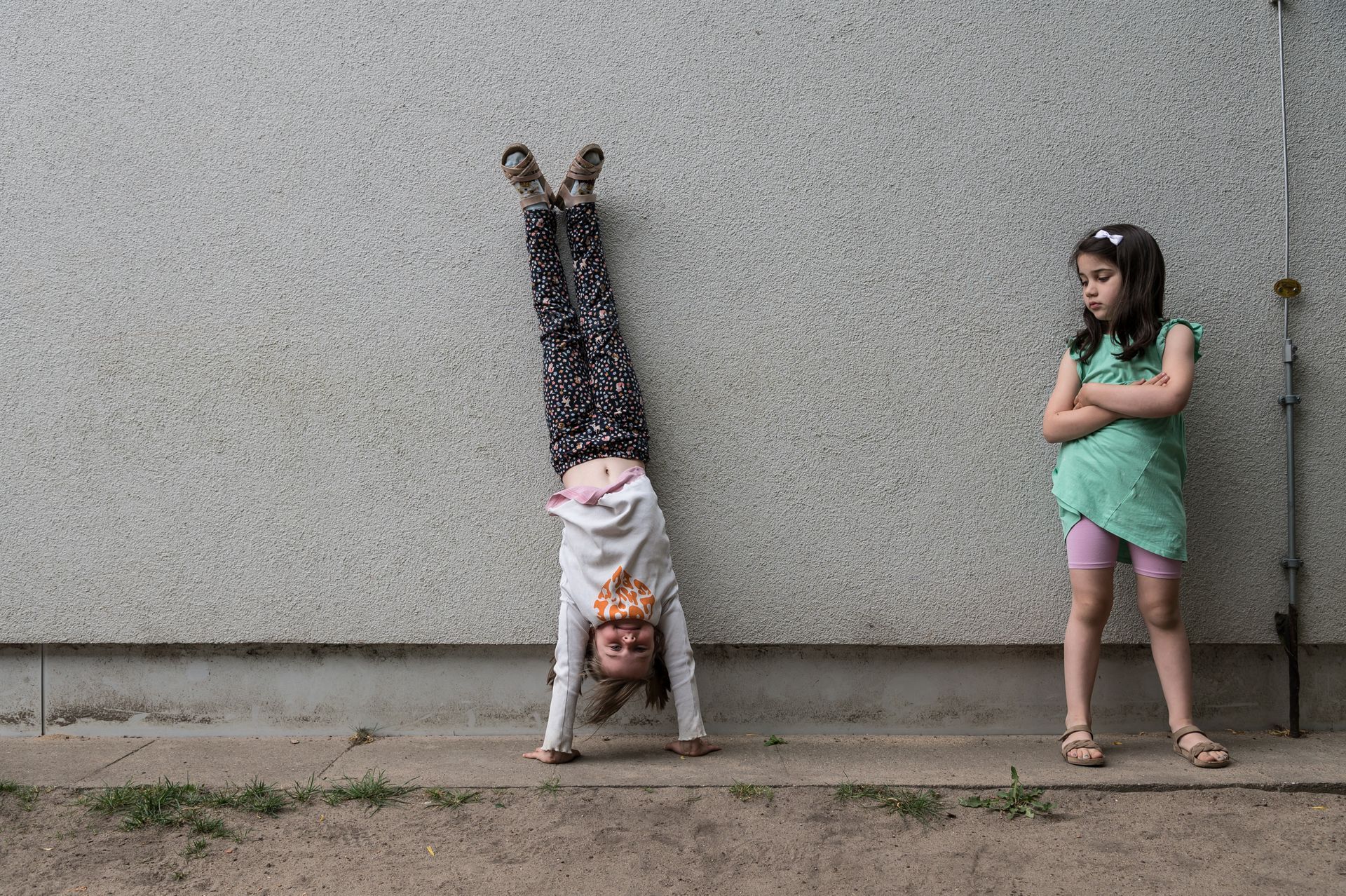 Zwei Kinder lehnen an einer Hauswand, eines davon mach einen HandstandReportage-Fotografie von WINTERPOL Hamburg