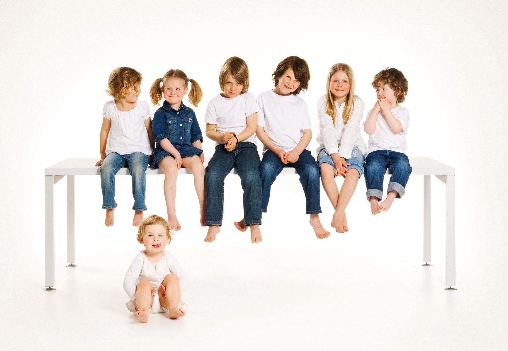 ip20 Prospekt-Motiv – Fotografie  von WINTERPOL Hamburg Sechs Kinder sitzen auf einem ip20-Tisch, ein weiteres Mädchen sitzt davor auf dem Boden, Werbefotografie aus Hamburg von Fotograf Kay Winter / WINTERPOL
