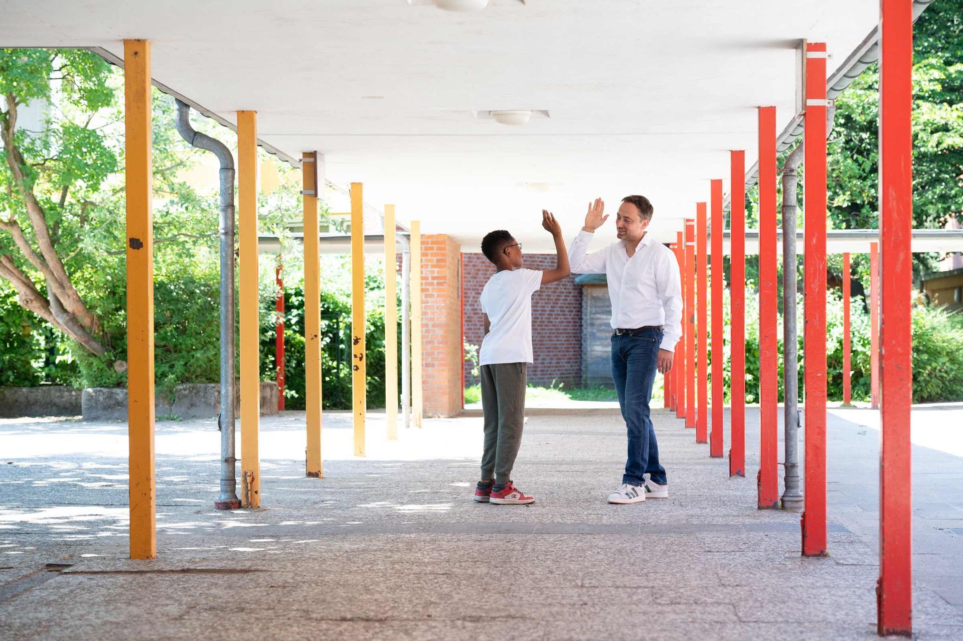 High Five zwischen Schulleiter und Schüler. Schulfotografie und Schulreportage-Fotografie aus Hamburg von Kay Winter / WINTERPOL