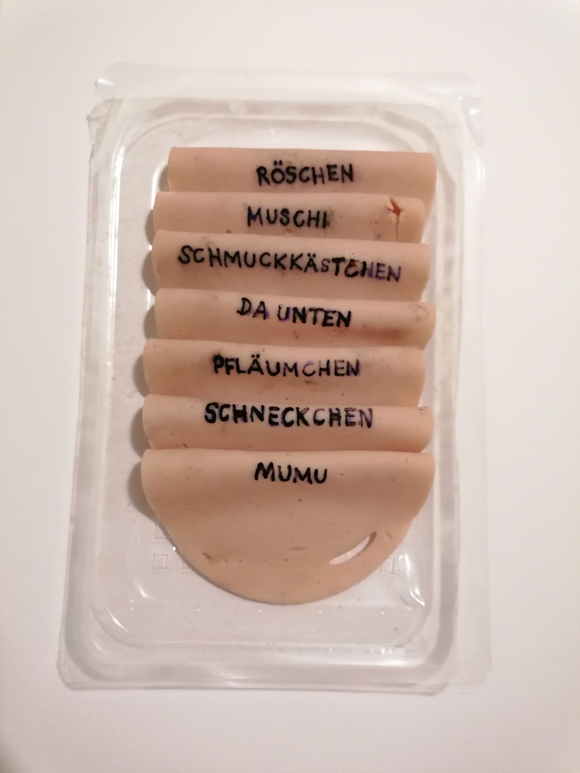 Wandinstallation einer goldenen Vulva aus Feuerdecke und Fotonegativen auf Tapete