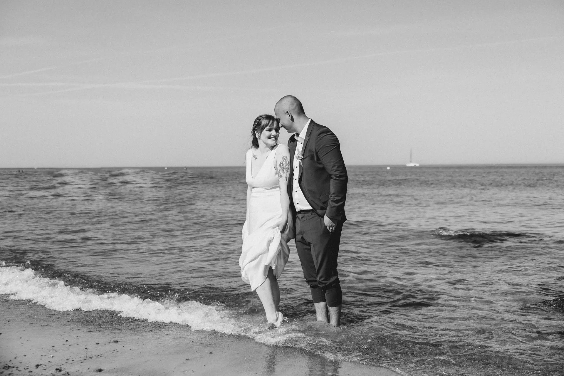 Brautpaar beim Fotoshooting am Strand von Kühlungsborn mit den Füßen im Wasser.