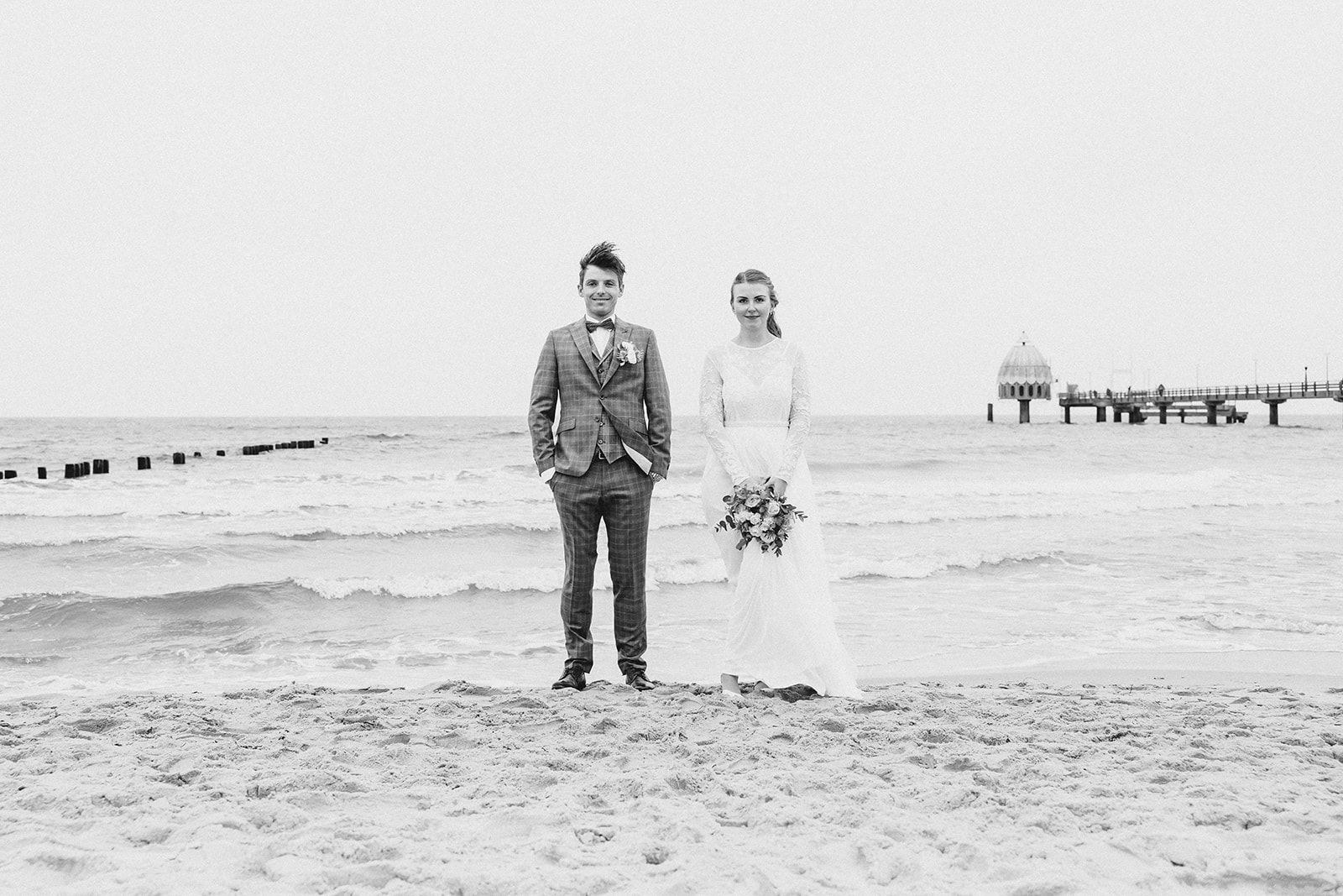 Lässiges Brautpaar beim Fotoshooting am Strand von Zingst mit Meerblick. Hochzeit im Kurhaus Zingst.