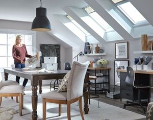 Woman standing in a room that has 3 Velux solar powered venting skylights with solar powered blinds