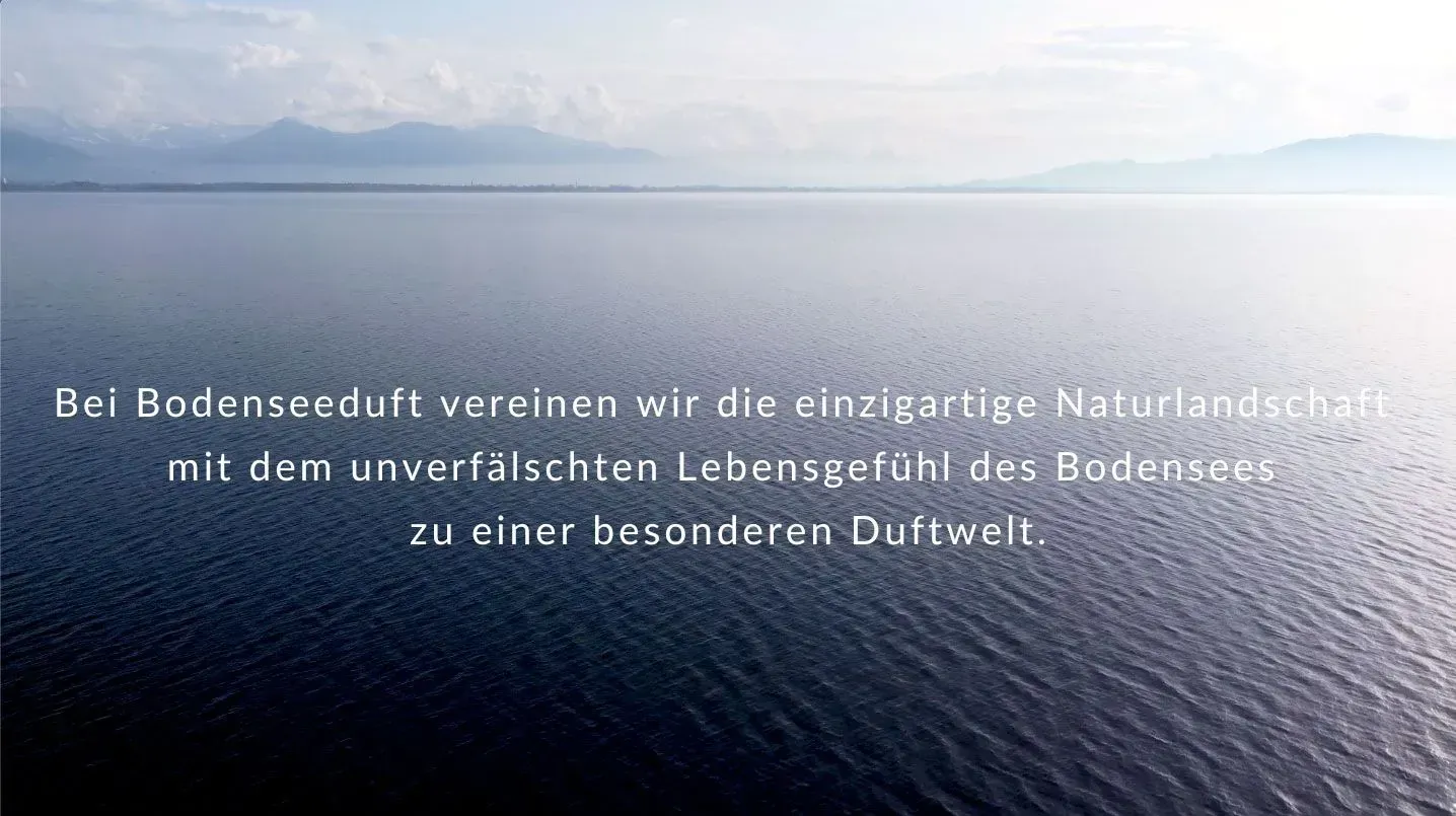 Blick über den Bodensee mit ruhigem Wasser und beeindruckender Bergkulisse - Inspiration für die Duftwelt von Bodenseeduft