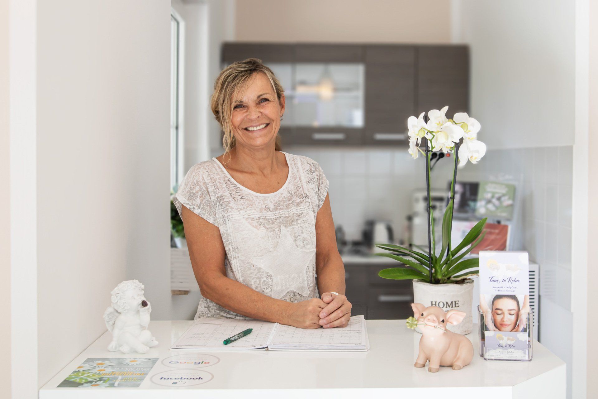 Inhaberin Ilka Schreiter des Kosmetikstudios Time to Relax in Berlin Lichtenrade. Frau lächelt in Kamera und steht am Tresen