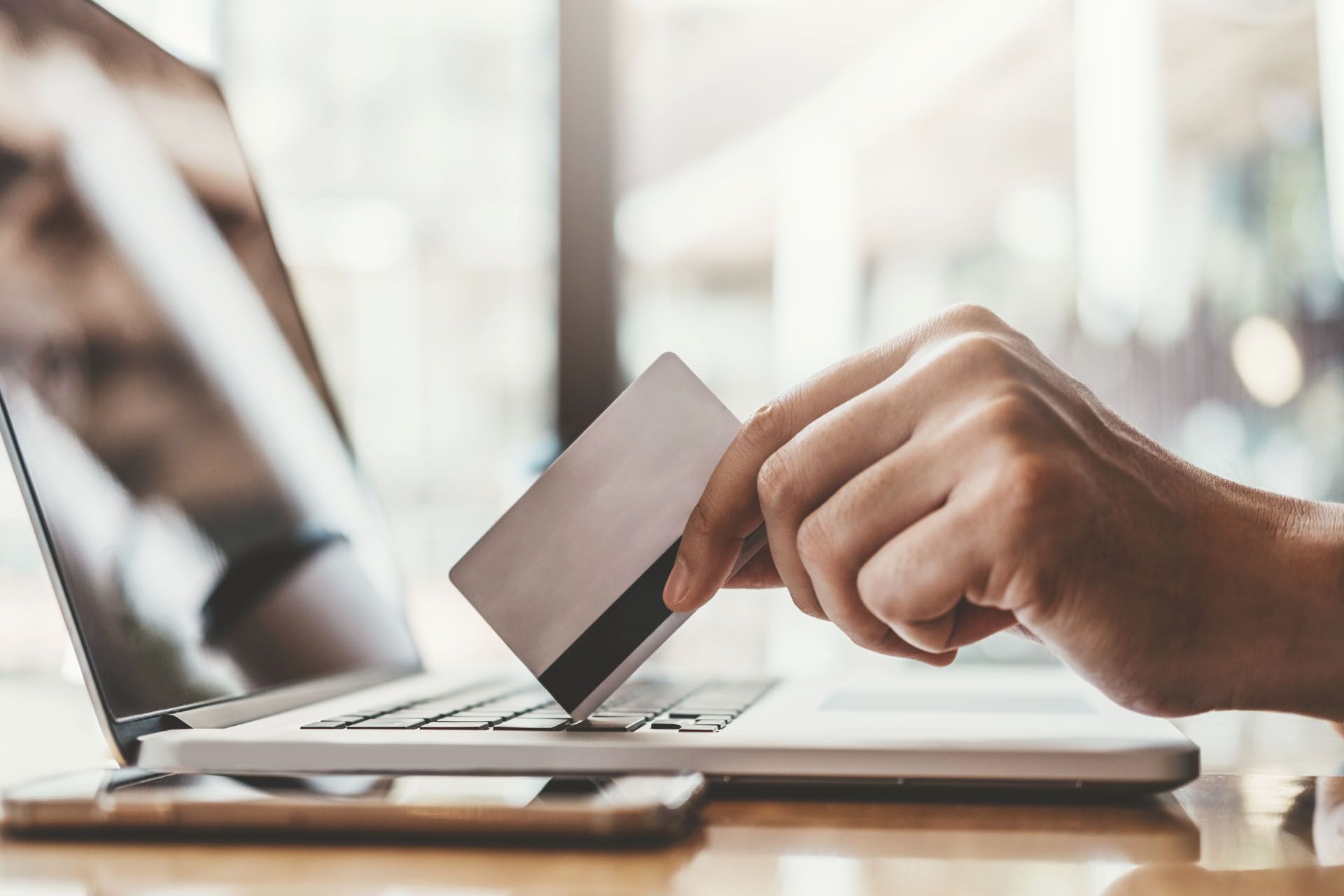Hand with credit card resting on laptop for online transfers