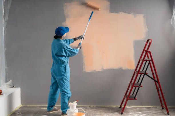A man in a blue suit is painting a wall with a roller, showcasing home office paint color options.