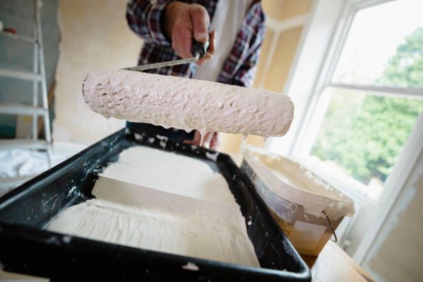 A man is painting a tray with a white substance, part of a home office paint color selection process.