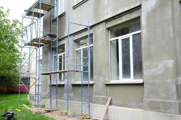 A building with scaffolding and windows, with workers painting the wood siding.