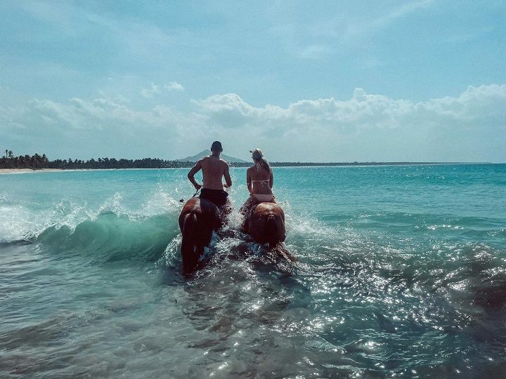 Reiten am Strand Zwei Reiter mit ihren Pferden im Meer