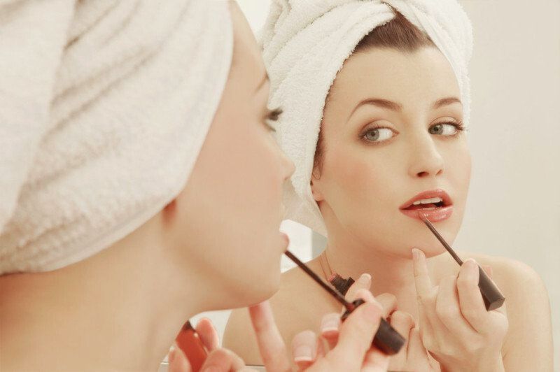 Frau im Bad, schminken, Spiegel, Make up, Hautpflege, schöne Haut, Lipglos, Lippen, Auftragen, Handtuch, atraktive Frau, Portrait, Nahautnahme, junge Frau, Spiegelung,