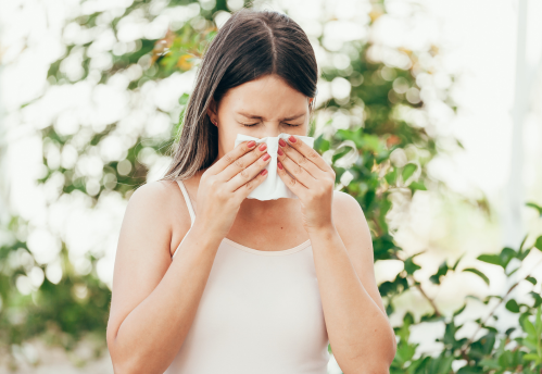 Frau mit Heuschnupfen schnaubt in Taschentuch