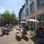 people sitting enjoying the sun outside the cupcake cafe margate town center with a clear blue sky