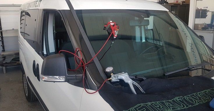 Riparazione parabrezza con la resina Una auto con parabrezza scheggiato durante la riparazione con resina e macchinario adatto