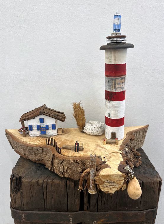 Miniaturlandschaft,Leuchturm auf Holzscheibe mit Häusschen und altem Mann auf Bank sitzend