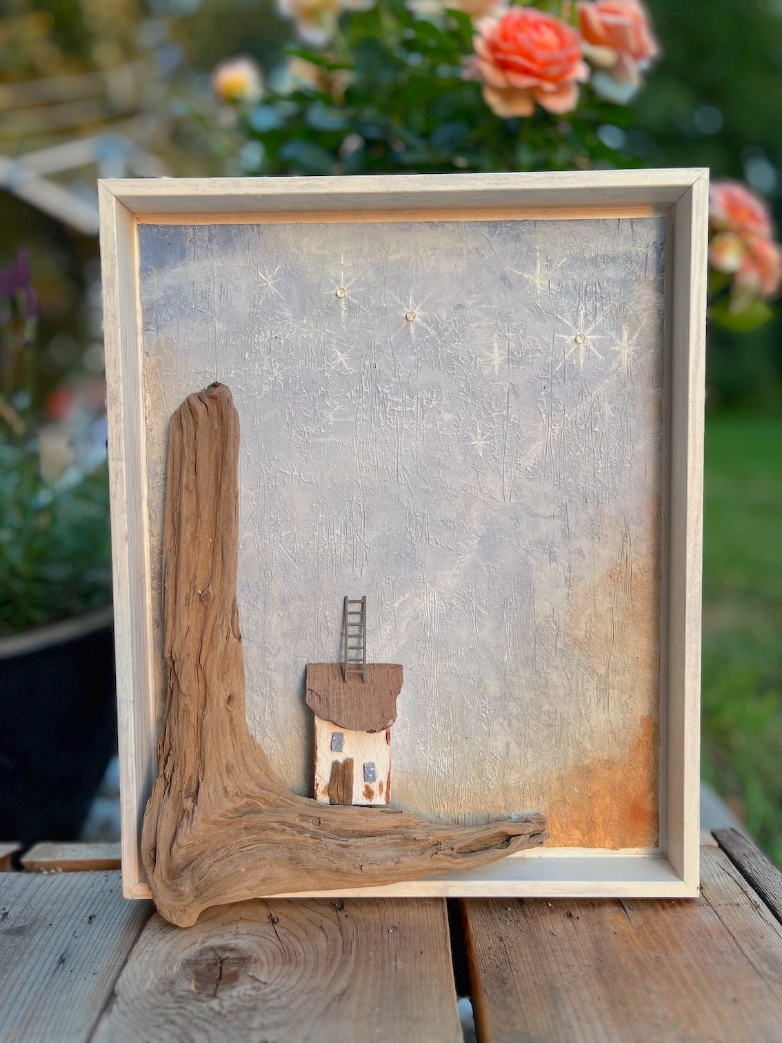 Treibholz-Ast mit Hütte und Leiter auf dem Dach. Im Schattenfugenrahmen, Hintergrund ein Himmel aus Aquarell.