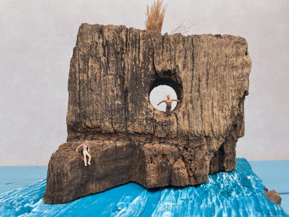 Altholz mit Loch, 2 Miniaturfiguren die ins Wasser springen