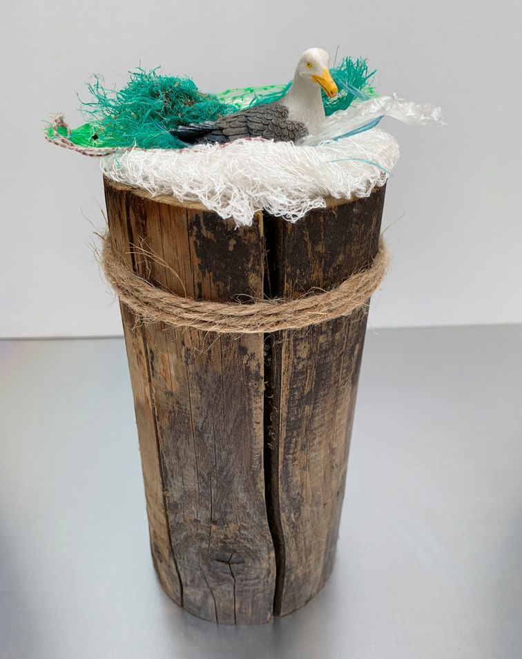 Möwennest aus Plastikmüll auf Holzpfahl