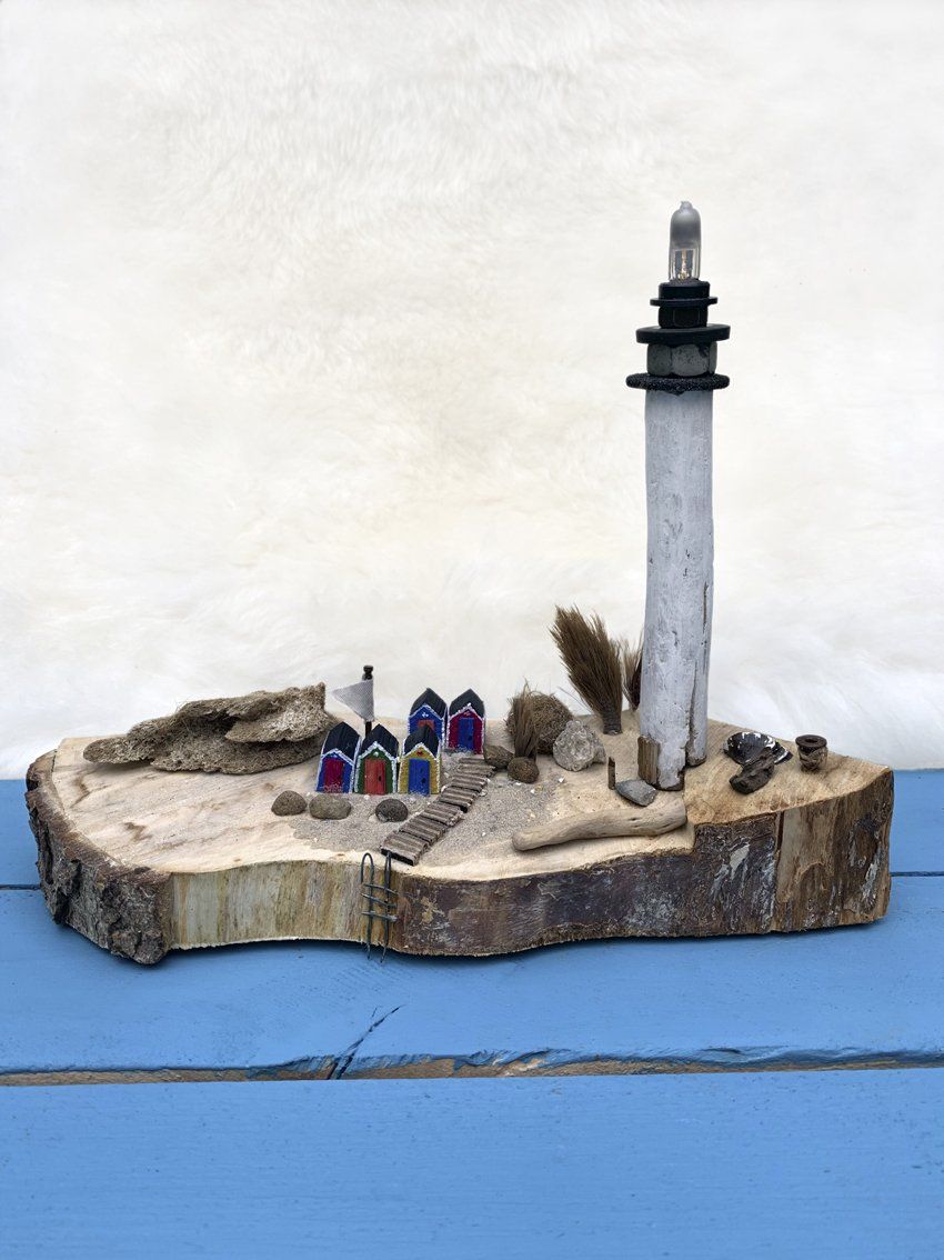 Miniaturlandschaft Leuchtturm und bunte Strand-Häuschen auf Baumscheibe
