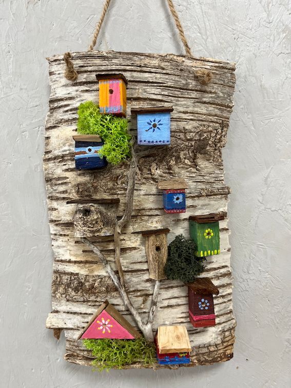 Birkenrinde bebaut mit kleinen bunten Vogelhäuschen und echtem Moos.