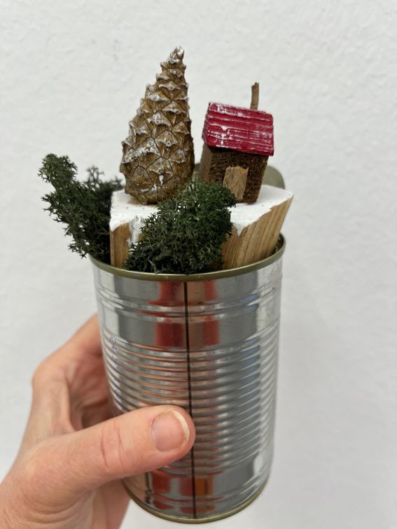 Blechdose gefüllt mit Winterlandschaftund einem Miniatur-Häuschen und Zapfen