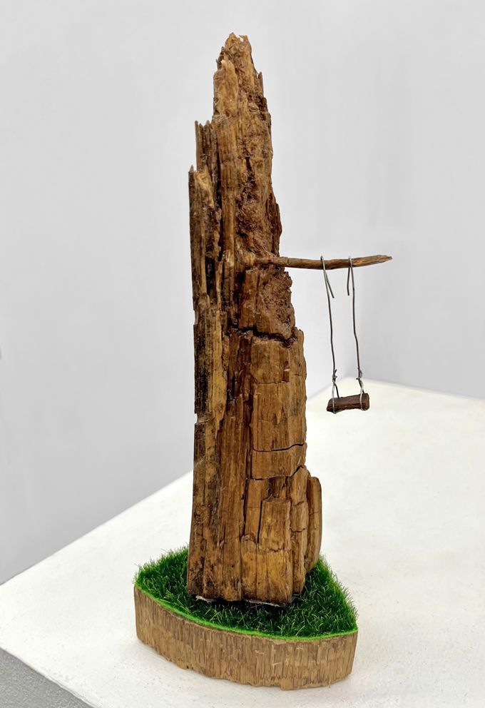 Eine Klippe aus Altholz, Kunstrasen,mit Schaukel aus Draht und Holz