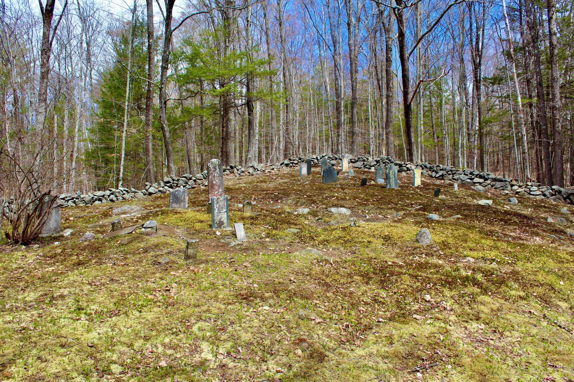 green hill surrounded by stonewalls with tombstones