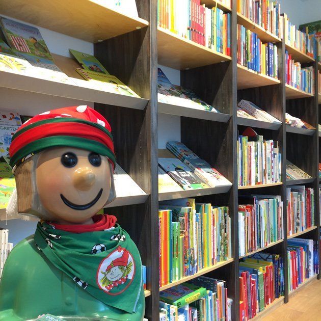 Pixi-Männchen vor dem Regal mit Kinderbübern für 0-6 Jährige