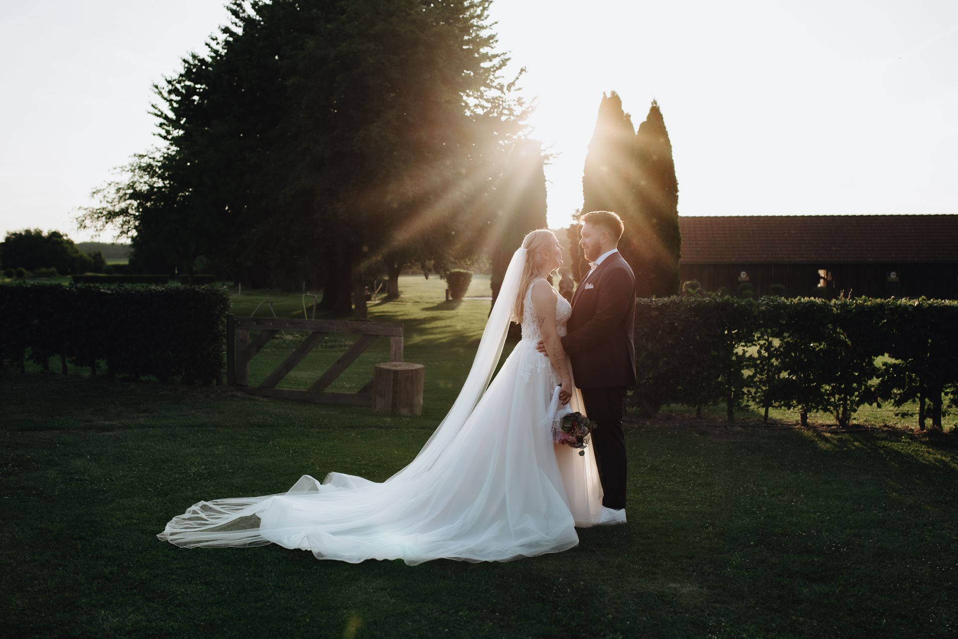 Brautpaar im Abendlicht in Köln Frechen in der Location Landbrenner. Brautkleid mit langer Schleppe und Schleier auf einem Golfplatz. Hochzeitsfotografin in Köln & Umgebung