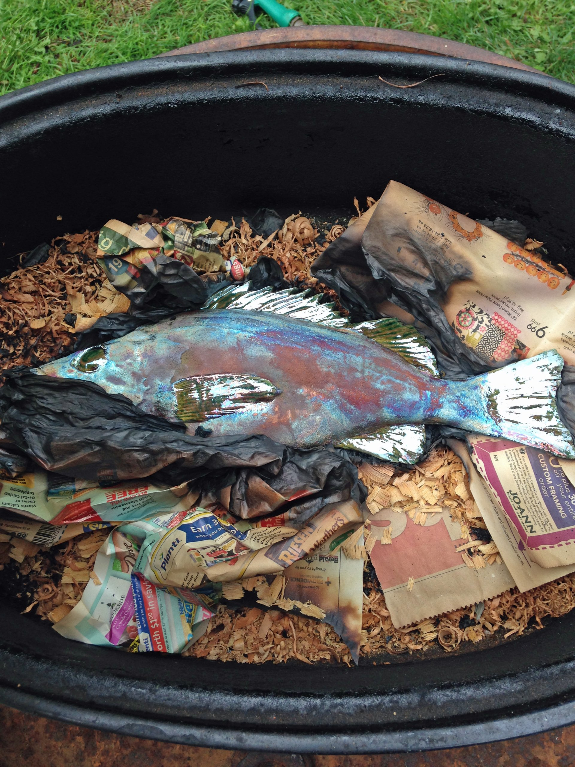 Cod sculpture in a raku burn barrel.