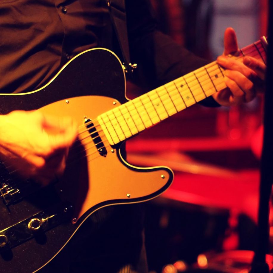 Bildausschnitt eines Rock-Konzerts, mit Gitarrist an einer E-Gitarre