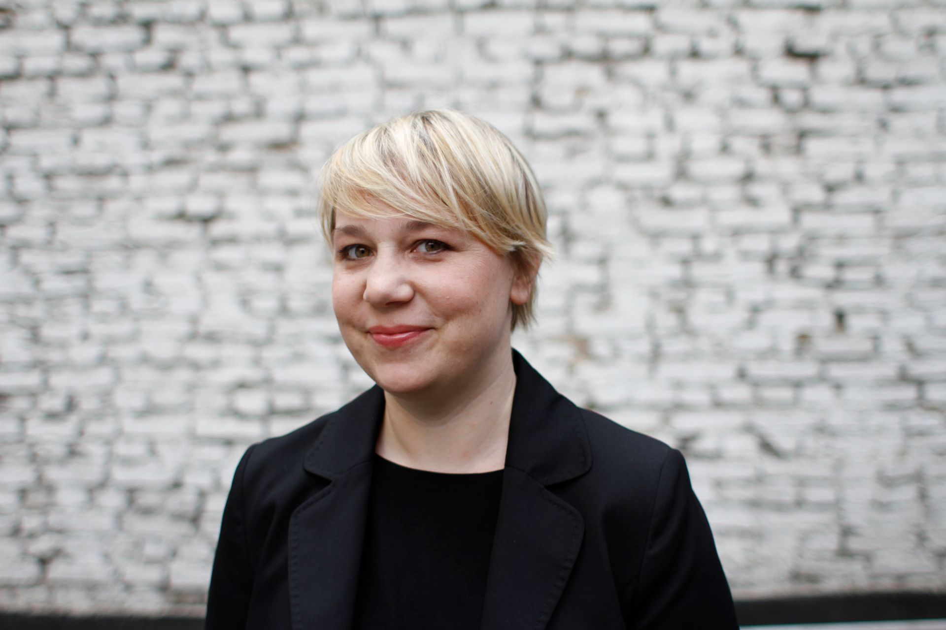 Annette Ziegert vor einer weißen Mauer stehend und in die Kamera schauend.