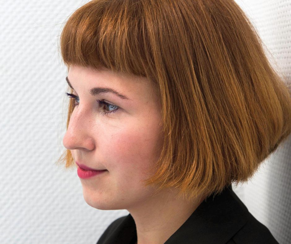 Großaufnahme das Gesichts von Jennifer Cierlitza von der Seite vor einem schlichen weißen Hintergrund.