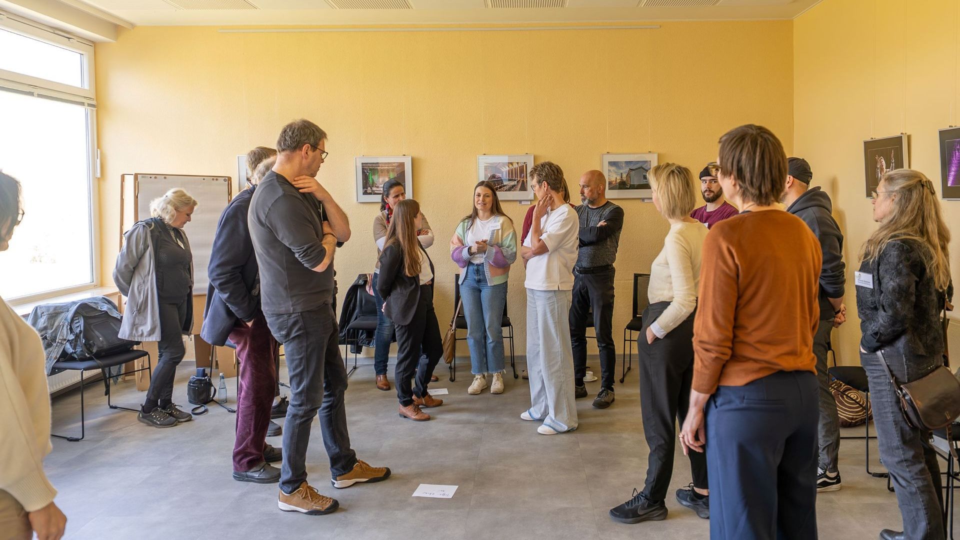 Die cirka 15 Teilnehmenden des Kulturlabors 1 stehen verstreut im Raum und diskutieren.