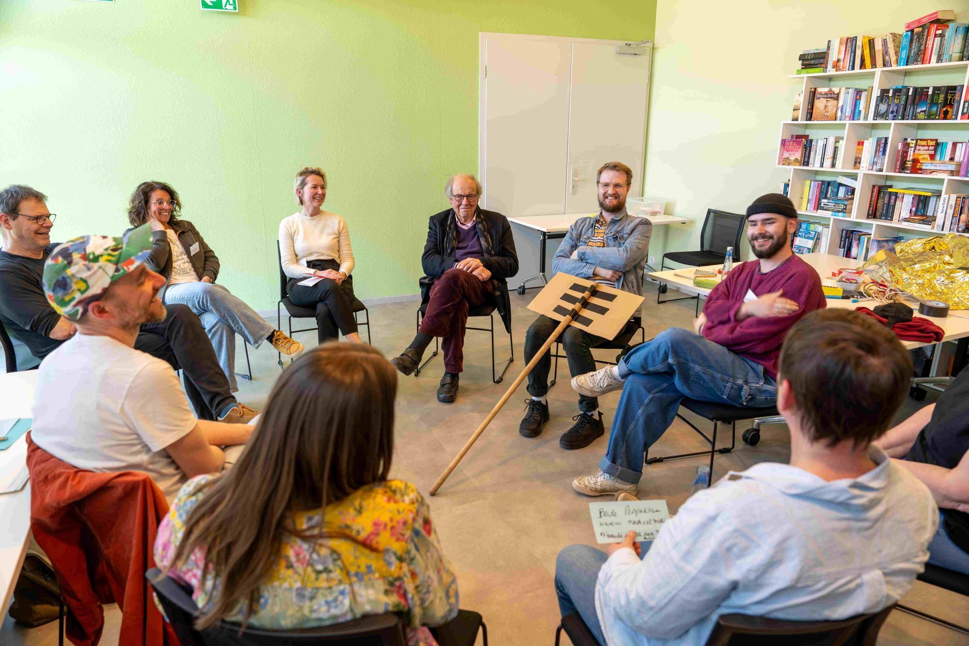 Unterschiedliche Menschen - alt, jung, unterschiedliche Communitys - sitzen in einem Stuhlkreis, diskutieren und lachen