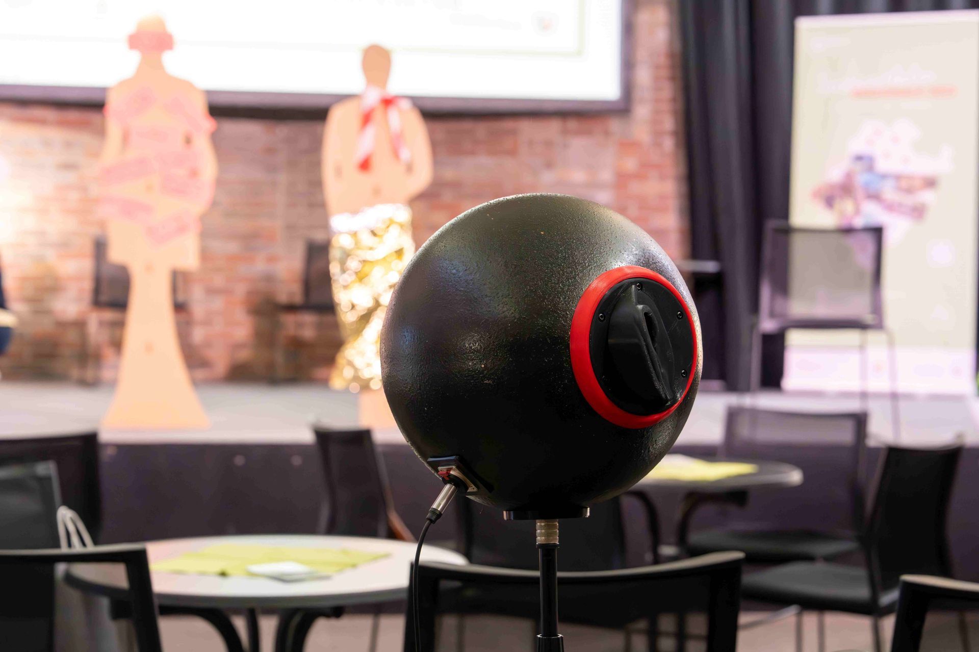 Kunstkopf für eine 3D-Aufnahme,im Hintergrund ist die Bühne mit Kulturpersonas zu sehen.