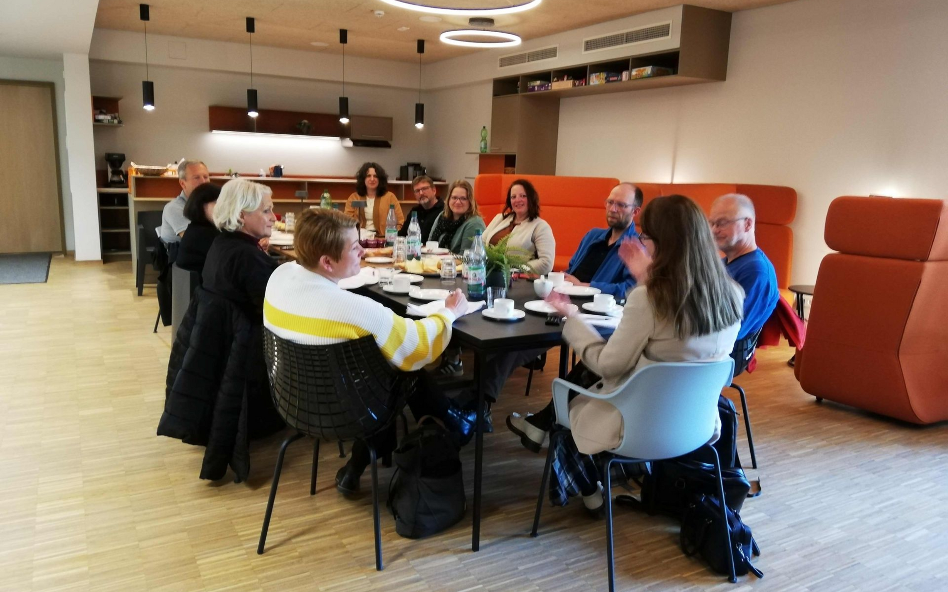 10 Menschen sitzen an einem Tisch und diskutieren.