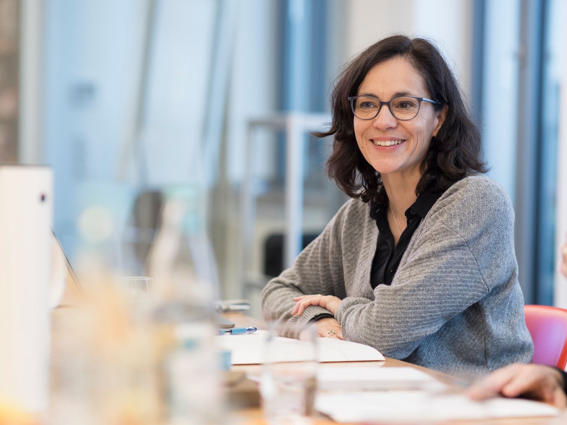 Catalina Rojas Hauser sitzt lächeln an einem Konferenztisch.