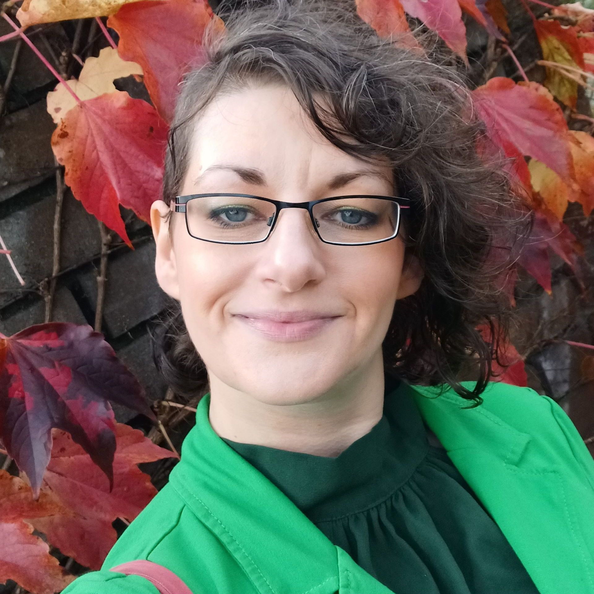 Sina Kraus steht vor Herbstblättern und lächelt in die Kamera.