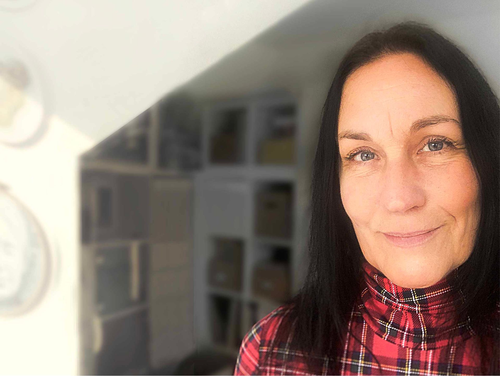 Sandra Hertel sitzt vor einer alten Bruchsteinmauer, rechts neben ihr steht eine alte Kaffeemühle.